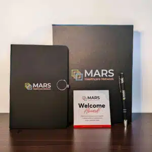 Premium appreciation box open showing branded notebook, metal pen, and greeting card