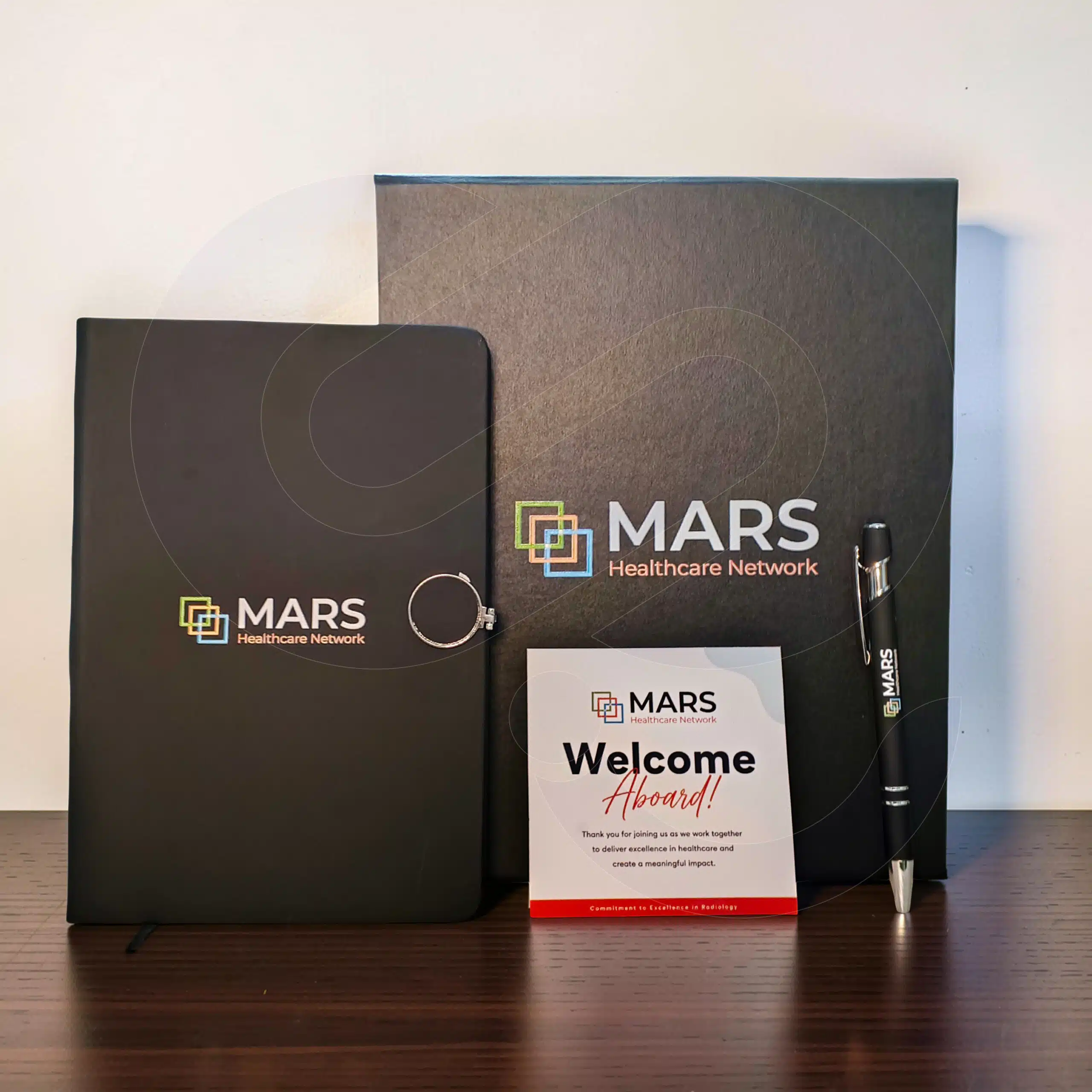 Premium appreciation box open showing branded notebook, metal pen, and greeting card